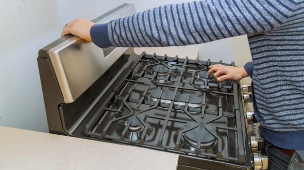close up of person pulling stove out from wall